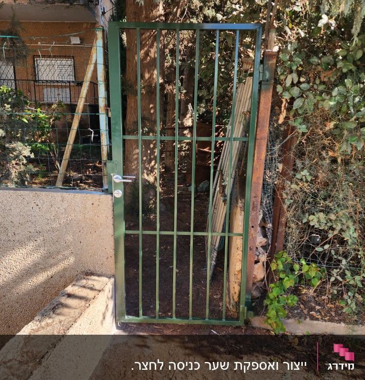 שער מתכת ירוק עם סורגים אנכיים בגינה
